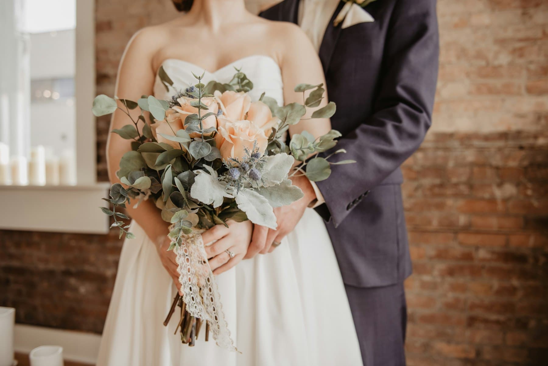 La novia sostiene un ramo de rosas y eucalipto junto al novio